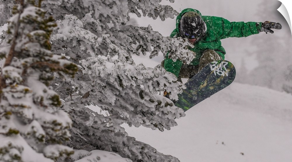 Action shot of a snowboarder in green doing a grab mid-air.