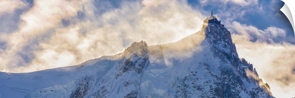 Photograph of Mont Blanc surrounded by sunlit clouds.