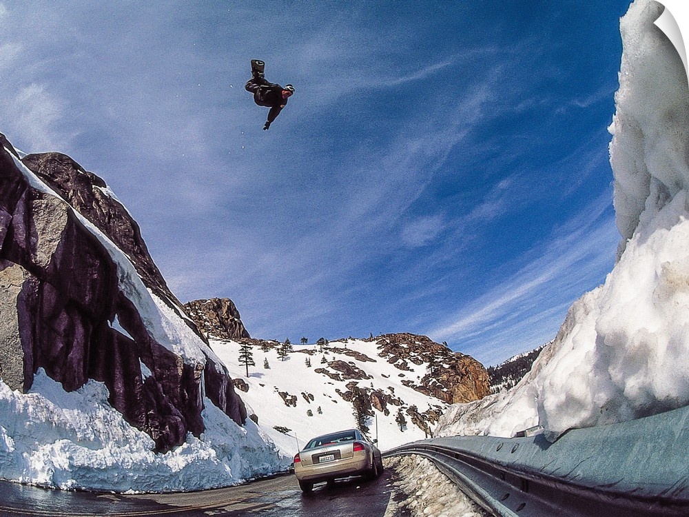 Nate Mott flying on his snowboard over the Donner Summit, as a car passes by below, California, mid 90s.