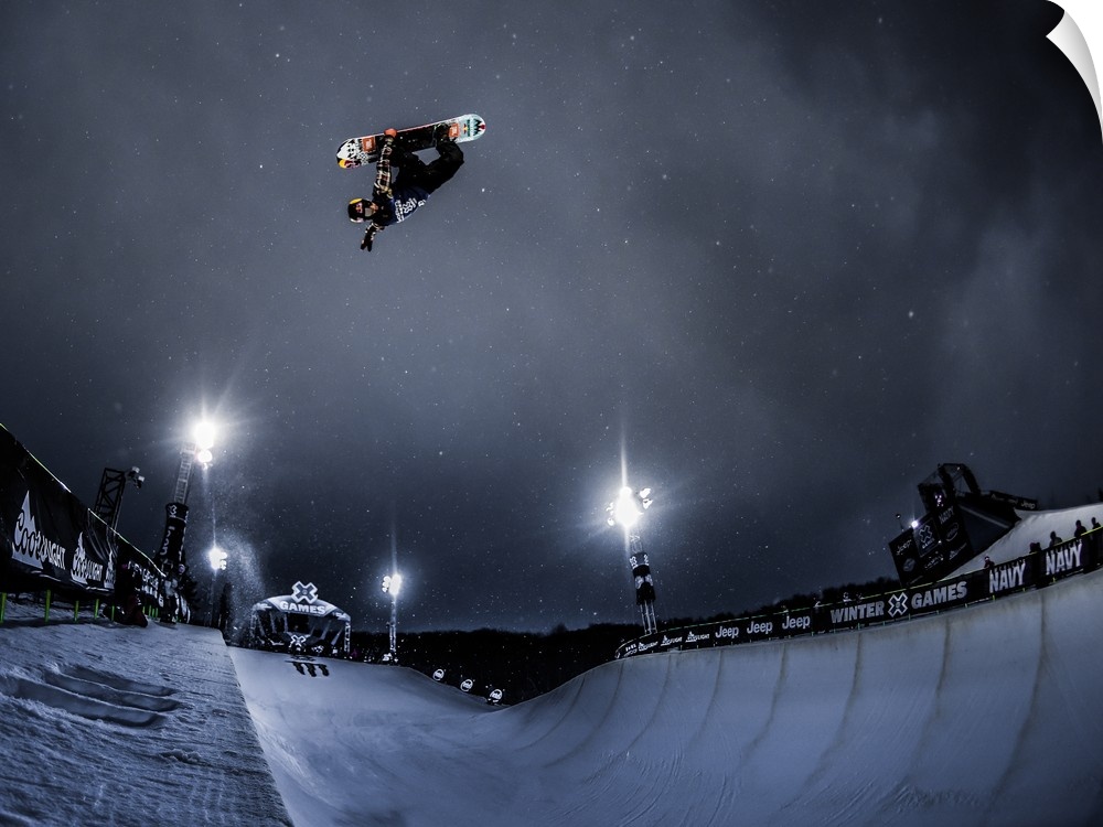 Snowboard performing a trick in the air over a course at night, XGames, Aspen, Colorado, 2016.