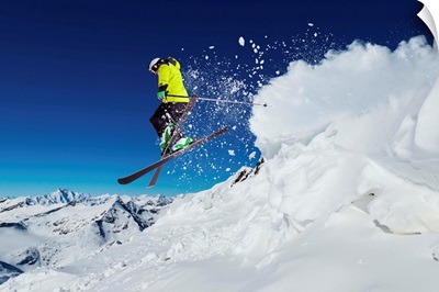 Alpine skier skiing downhill, blue sky in background