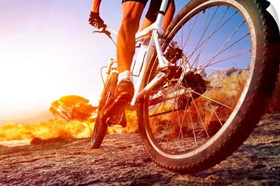 Cyclist riding a mountain bike on a rocky trail at sunrise