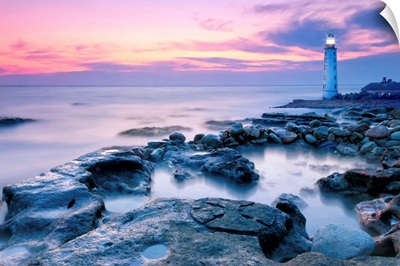 Lighthouse On Rocky Coastline At Sunset