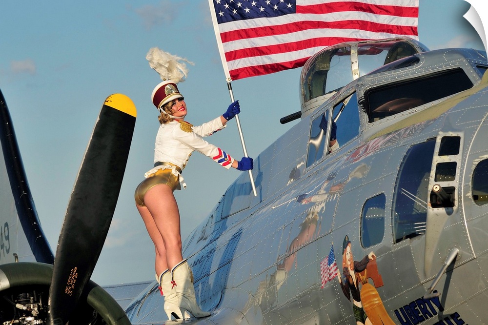 Patriotic 1940's style majorette pin-up girl standing on a B-17 bomber with an American flag.