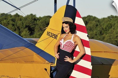 1940's style pin-up girl leaning on the tail fin of a Stearman biplane