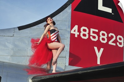 1940's style pin-up girl standing on the tail of a B-17 bomber