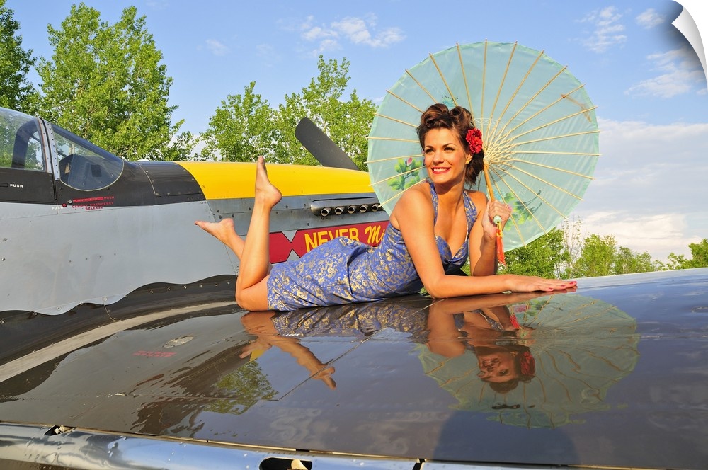 Beautiful 1940's style pin-up girl with parasol on a vintage P-51 Mustang.