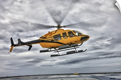 A Bell 407 utility helicopter prepares to land on an oil rig