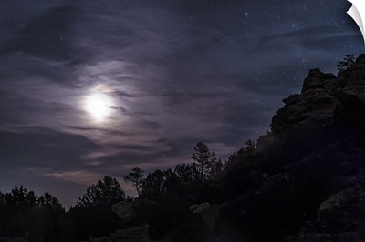 A bright moon rises through clouds over a hill in Oklahoma