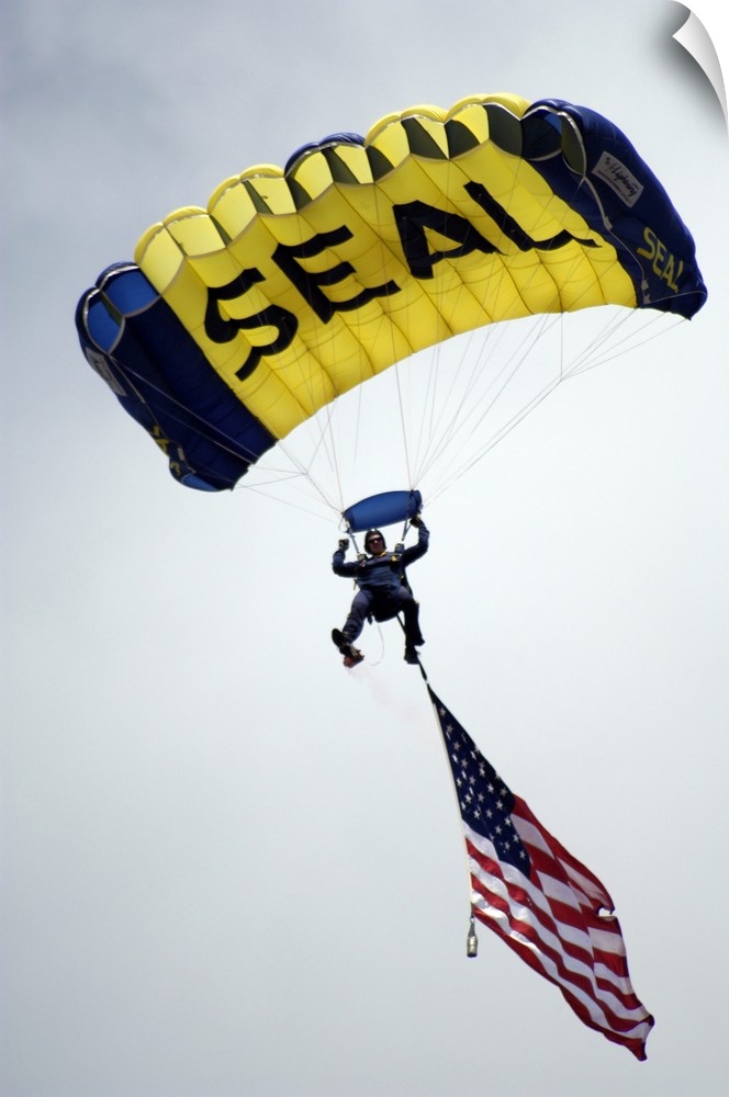 A member of the U.S. Navy Parachute Team descend through the sky with the American flag.