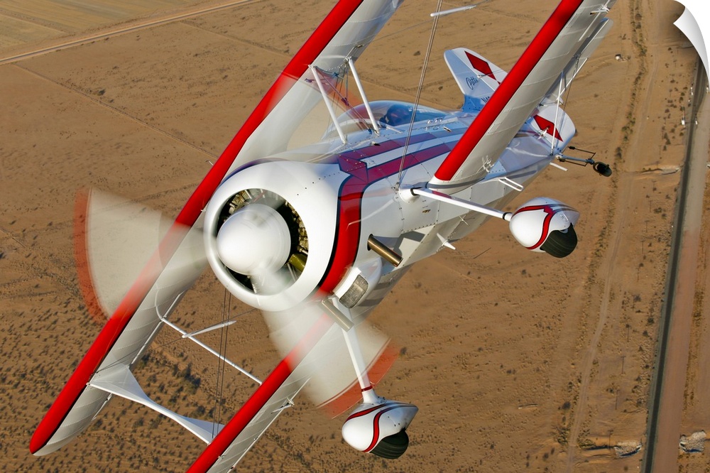 Closely taken photograph of an airplane as it begins to turn high in the sky over a desert field.