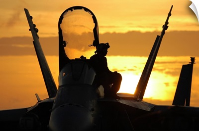 A plane captain enjoys a sunset from atop an F/A-18 Hornet