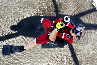 A rescue swimmer gets hoisted into an MH-60 Jayhawk helicopter