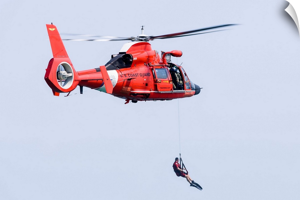 A rescue swimmer is lowered from a U.S. Coast Guard HH-65 Dolphin helicopter.