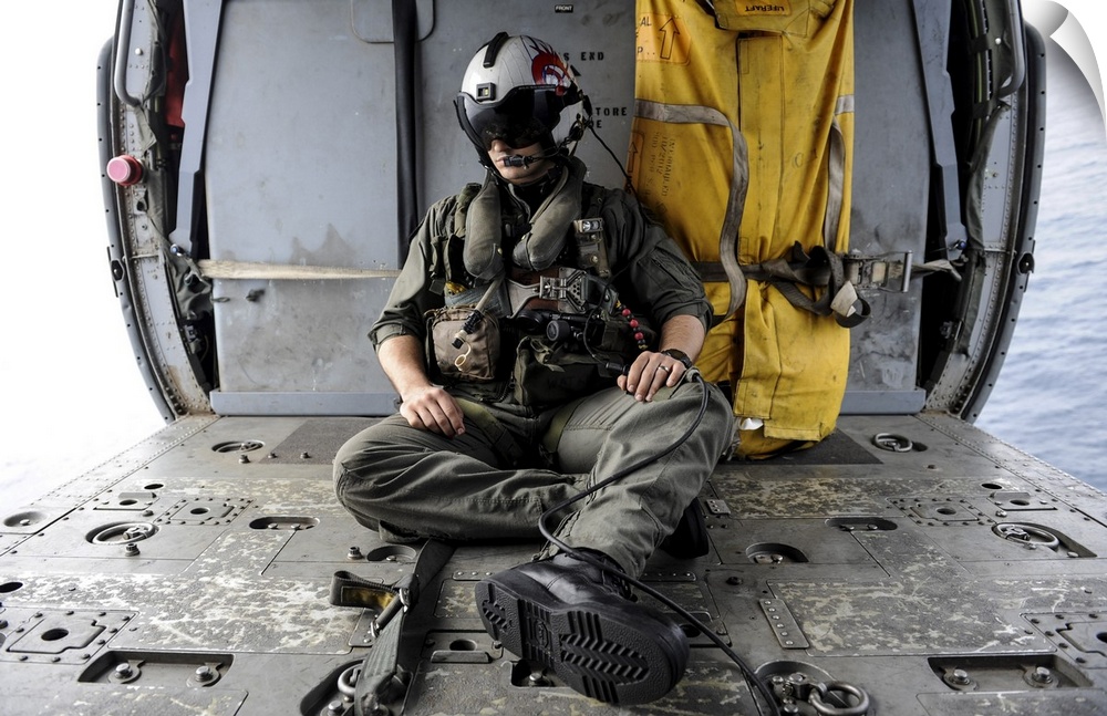 Arabian Sea, August 29, 2013 - A search and rescue swimmer sits in the back of an MH-60S Sea Hawk helicopter.
