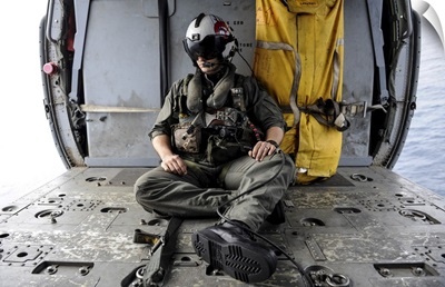 A Search And Rescue Swimmer Sits In The Back Of An MH-60S Sea Hawk