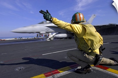 A shooter signals the launch of an F/A-18 Super Hornet