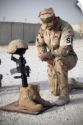 A soldier bows to pay tribute to a fallen soldier