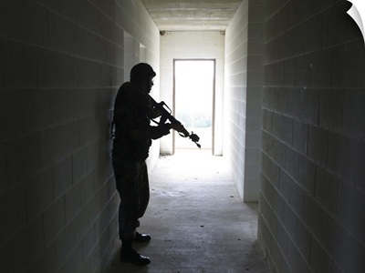 A soldier clears a hallway at a Military Operation in Urban Terrain training facility