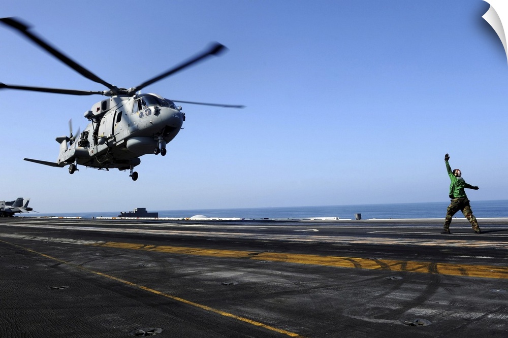 Arabian Sea, October 24, 2011 - Airman directs an EH-101 Merlin helicopter onto the flight deck aboard the Nimitz-class ai...