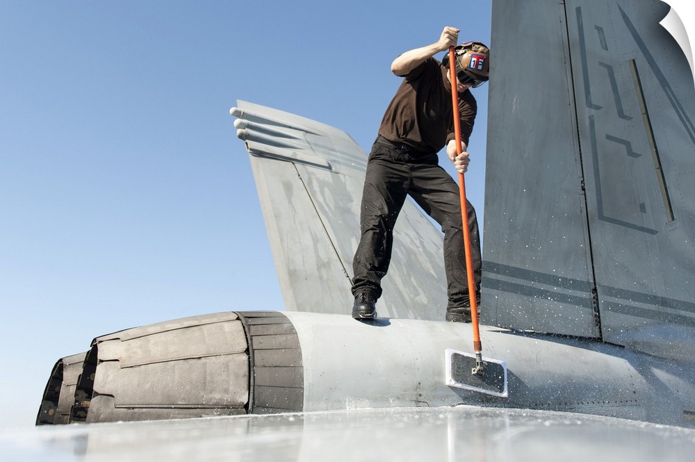 Gulf of Oman, February 16, 2014 - Airman washes an F/A-18F Super Hornet on the flight deck of the aircraft carrier USS Har...