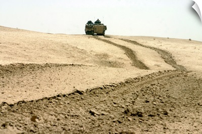 An amphibious assault vehicle rolls through a desert field