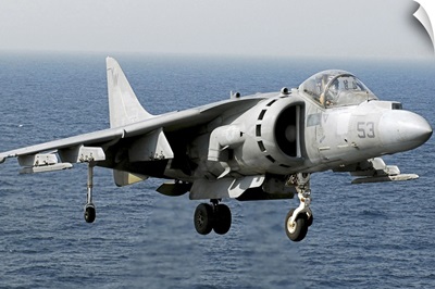 An AV-8B Harrier hovers over the flight deck of USS peleliu