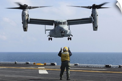 An aviation boatswain's mate directs the landing of an MV-22 Osprey