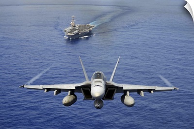 An F/A-18E Super Hornet flying above USS John C. Stennis