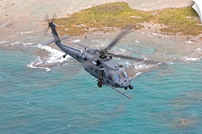 An HH-60G Pave Hawk flies along the coastline of Okinawa, Japan