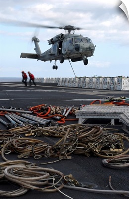 An HH-60H Seahawk helicopter prepares to lift a crate of ordnance