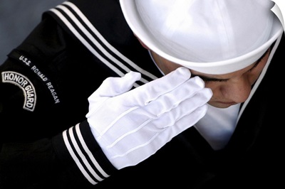 An Honor Guard member renders a salute during a burial at sea ceremony