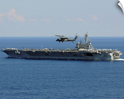 An MH 60S Seahawk helicopter flies over USS George H.W. Bush