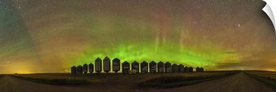 Aurora borealis behind grain bins on a country road in Alberta, Canada