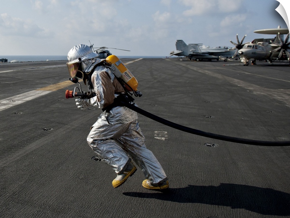 Arabian Sea, January 13, 2012 - Aviation Boatswain's Mate carries a fire hose during a flight deck fire drill aboard the N...