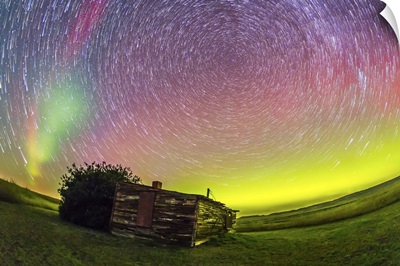 Fish-eye lens composite of aurora and circumpolar star trails above ranch in Canada