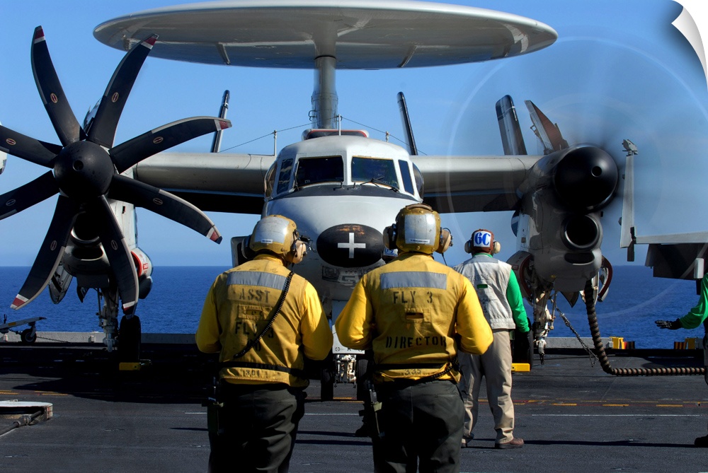 Flight deck directors watch as pilots of an E2C Hawkeye startup their engines