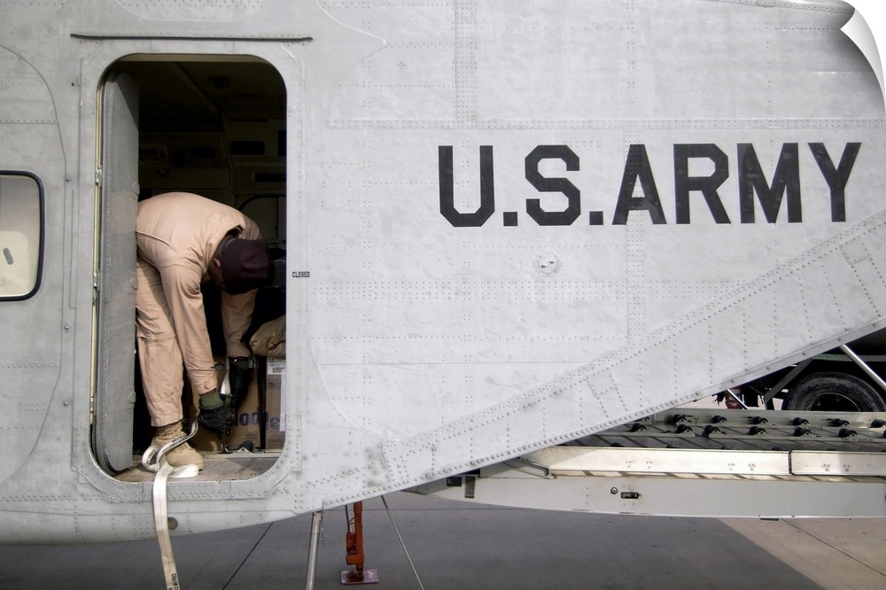 U.S. Army Flight Engineer secures equipment inside the cargo compartment of his C-23B Sherpa aircraft prior to departing f...