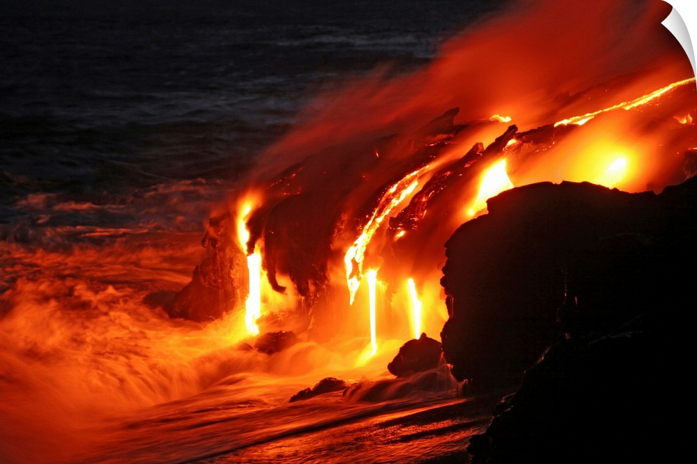 Photograph of magma running off a rock into the ocean at night.