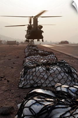 Marines attach sling loads to the body of an Army CH47 Chinook cargo helicopter
