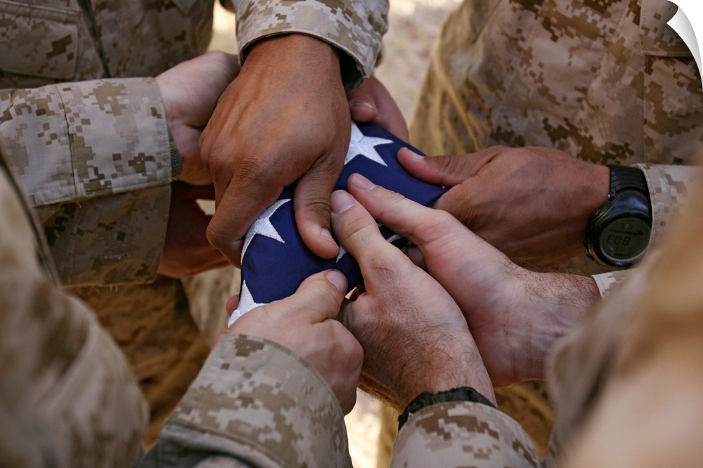 Photograph of soldiers' hands holding star covered fabric.