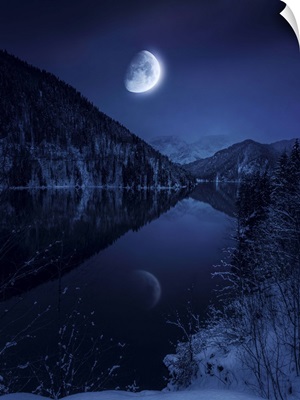 Moon rising over tranquil lake in misty mountains