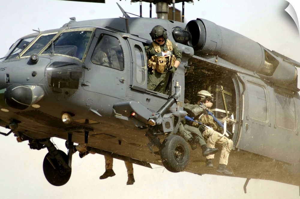 Pararescuemen aboard a helicopter prepare for landing