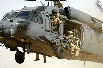 Pararescuemen aboard a helicopter prepare for landing