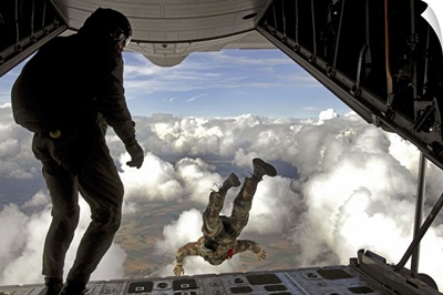 Pararescuemen jump out the back of a C130 Hercules