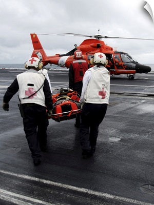 Personnel Carry An Injured Sailor To A Coast Guard MH-65 Dolphin Helicopter