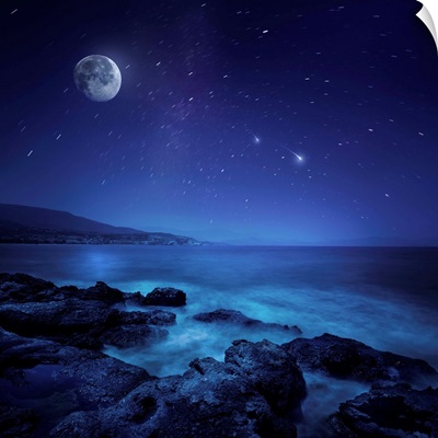 Rocks seaside against rising moon and starry field, Crete, Greece