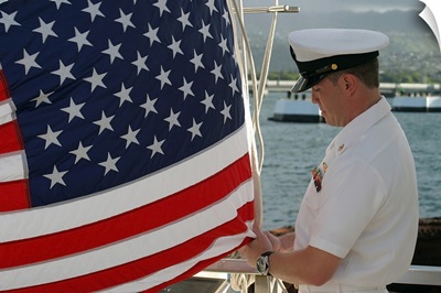 Sailor raises an American flag above the USS Arizona Memorial in Pearl Harbor, Hawaii