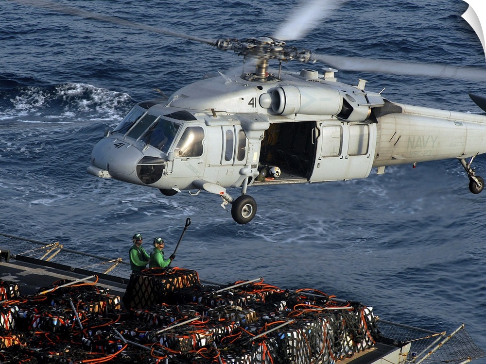 Sailors attach pallets of supplies to an MH-60S Knighthawk.