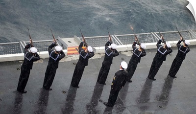 Sailors fire a 21-gun salute during a burial at sea ceremony